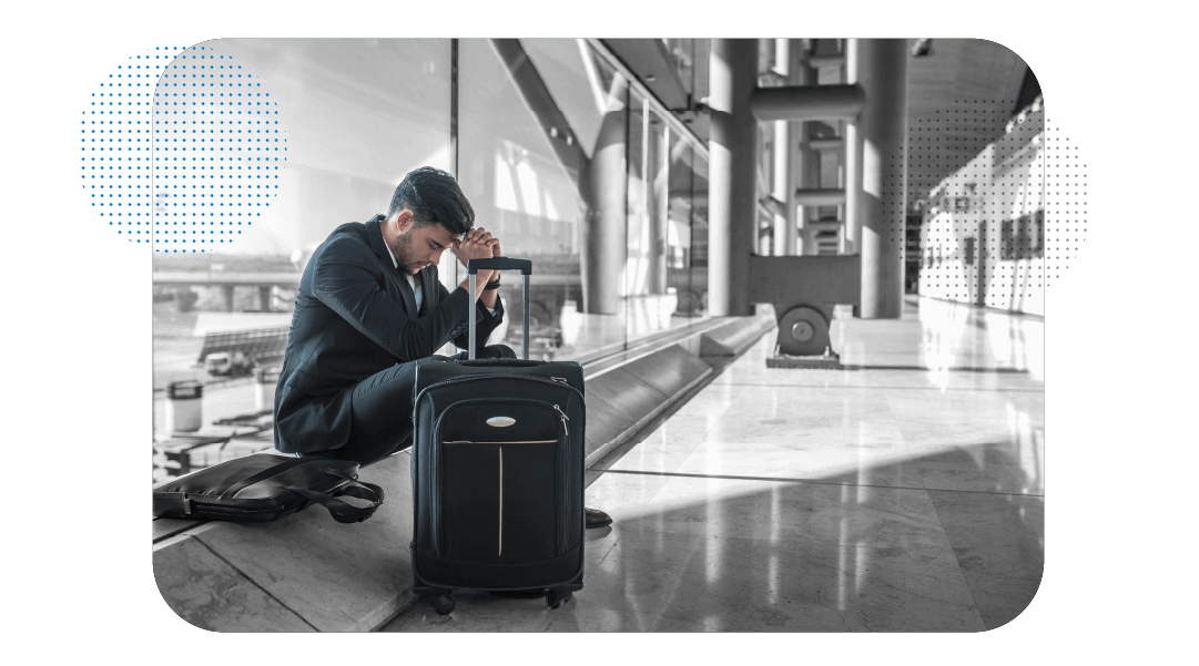 Homem sentado em um aeroporto, com a mala ao lado.
